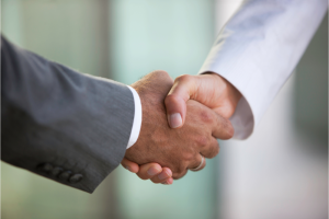 A close up shot of two CRM consultants in suits shaking hands